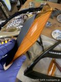 手袋をはめた手で、トヨタ20プリウスのヘッドライト用オレンジリフレクターを加工している様子