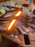 作業台の上でオレンジ色のライン全体が点灯している、加工中のトヨタ20プリウスのヘッドライト
