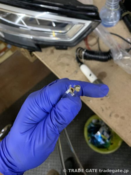 焼損した導光チューブを青色の手袋で持った作業写真、焼けた跡が見える