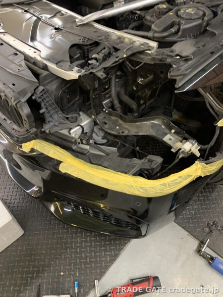 BMW G30 5シリーズのフロントバンパーを一部ずらし、ヘッドライト周辺の作業スペースを確保している様子。