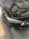 ボンネットが開けられたBMW 4シリーズ F34のエンジンルーム。ヘッドライト上部が見える。