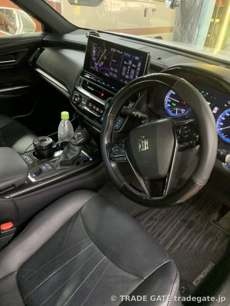 220系クラウンの運転席周りの内装。純正ナビ画面やカーボン調ステアリング、カップホルダーが確認できる。