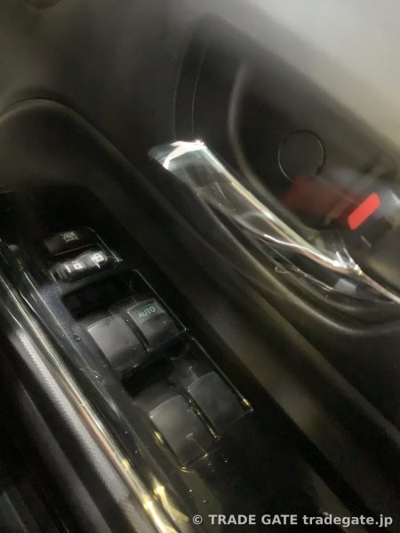 トヨタG'sアクアの運転席側パワーウィンドウスイッチ。スイッチは光っておらず、黒いプラスチックパネルに埋め込まれている。