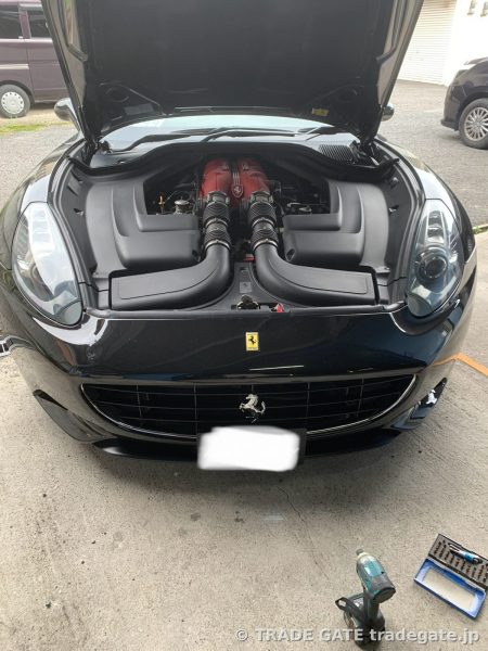 ボンネットが開いた黒いFerrari Californiaのフロント。エンジンルームと吸気ダクトが見える。