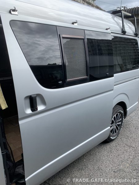 キャンピングカー仕様で開かれた左側スライドドアのハイエース