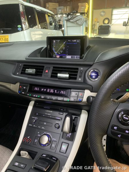 レクサスCT200hの車内、ダッシュボード中央の純正モニターにはナビ画面が表示され、エアコン操作パネルやシフトレバーが見える。